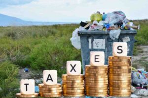 Cassonetto spazzatura, monete e scritta taxes