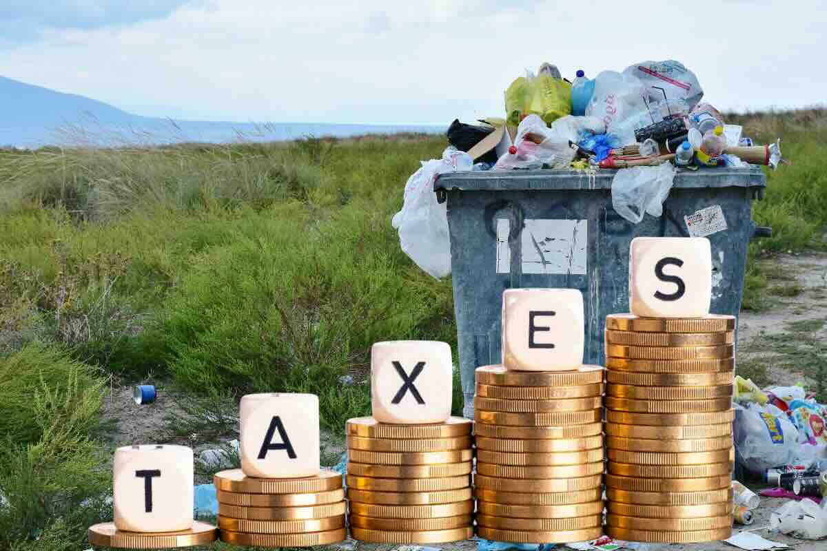 Cassonetto spazzatura, monete e scritta taxes