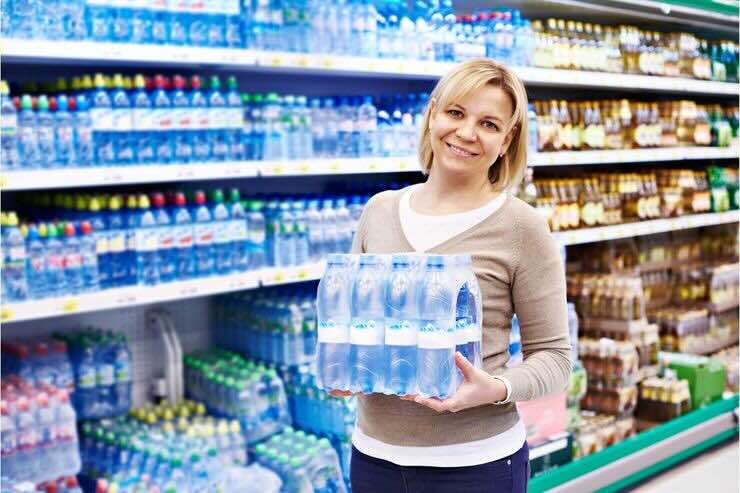 Donna con fardello d'acqua al supermercato